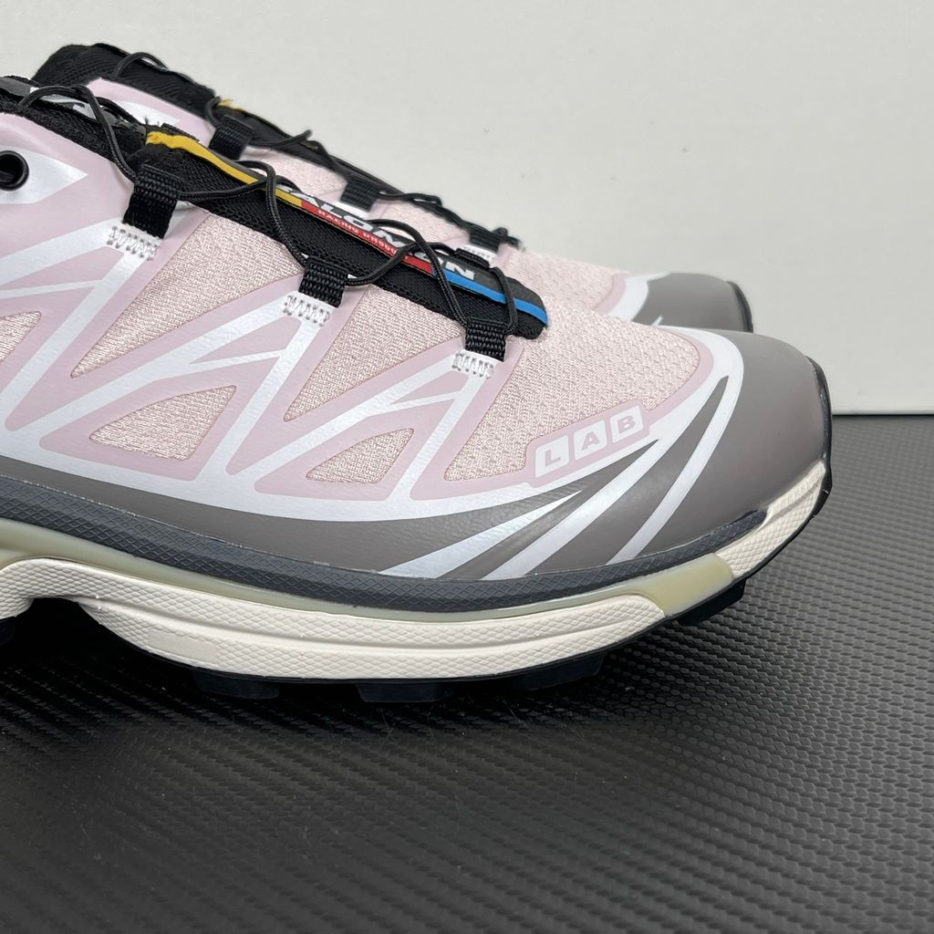 Side profile of the Salomon XT-6 trainers in a grey, white, and soft pink colorway, showcasing the technical mesh upper, "LAB" branding, and the cushioned ACS midsole.