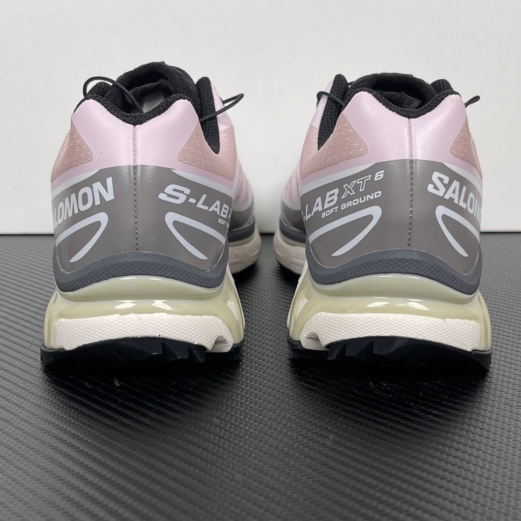 Side profile of the Salomon XT-6 trainers in a grey, white, and soft pink colorway, showcasing the technical mesh upper, "LAB" branding, and the cushioned ACS midsole.