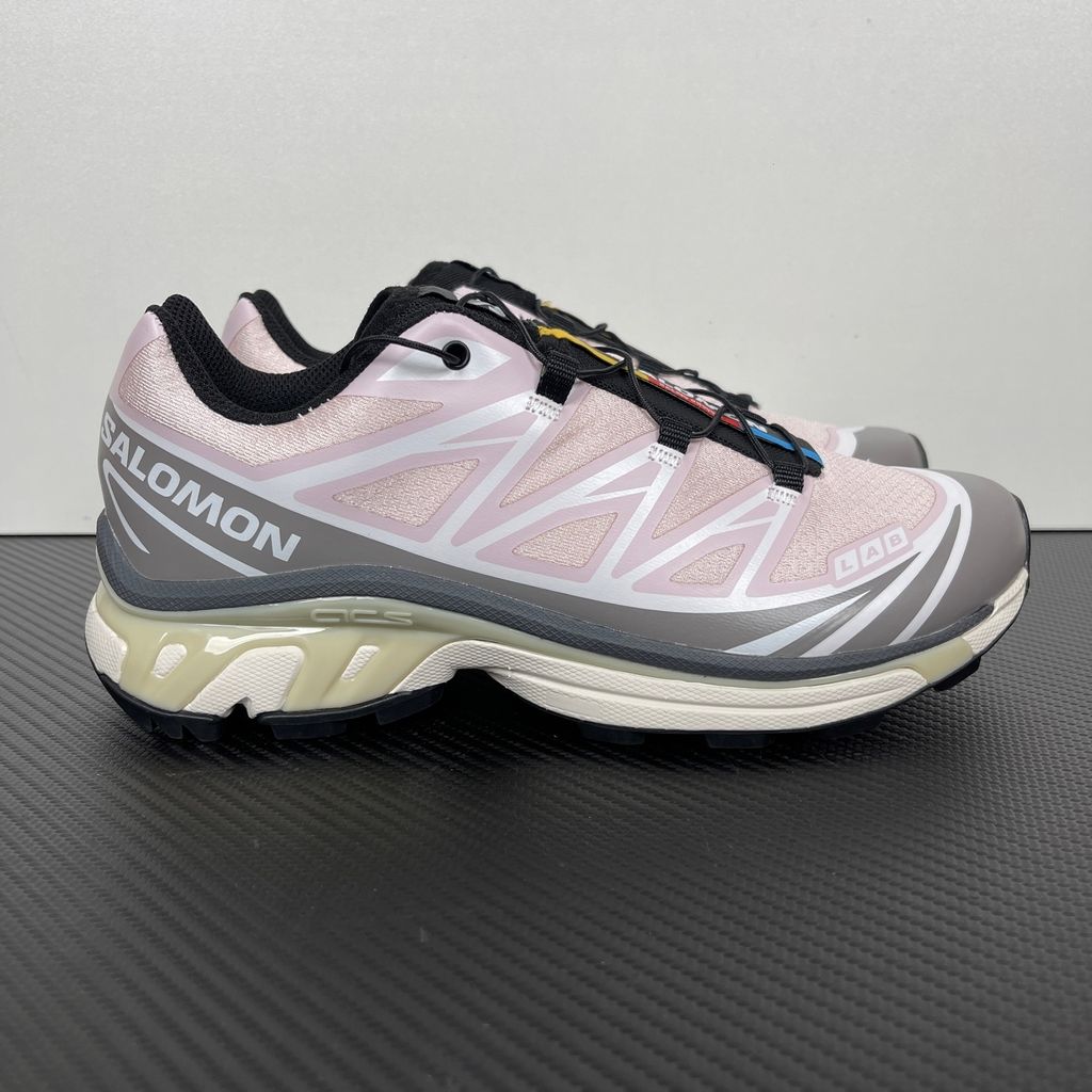 Side profile of the Salomon XT-6 trainers in a grey, white, and soft pink colorway, showcasing the technical mesh upper, "LAB" branding, and the cushioned ACS midsole.