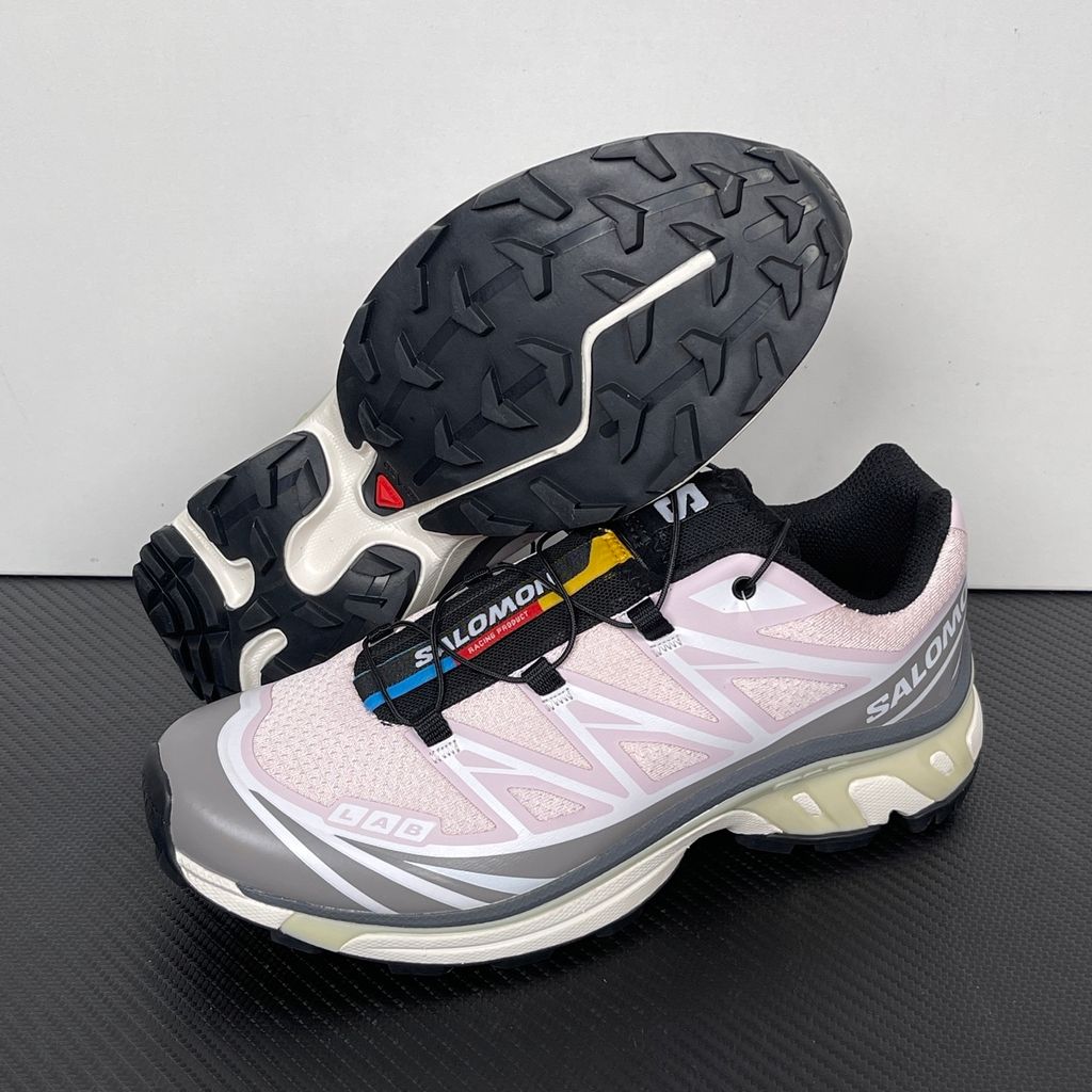 Side profile of the Salomon XT-6 trainers in a grey, white, and soft pink colorway, showcasing the technical mesh upper, "LAB" branding, and the cushioned ACS midsole.