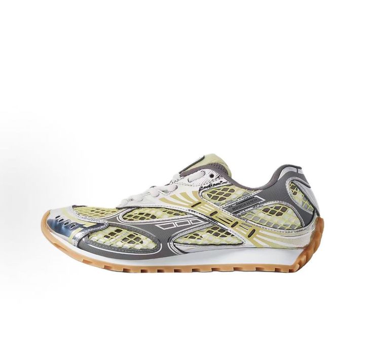 Side profile of the Bottega Veneta Orbit Runner sneaker, showcasing its intricate metallic and green-yellow technical mesh construction, prominent "BOTTEGA VENETA" branding, and the textured gum-tone outsole.