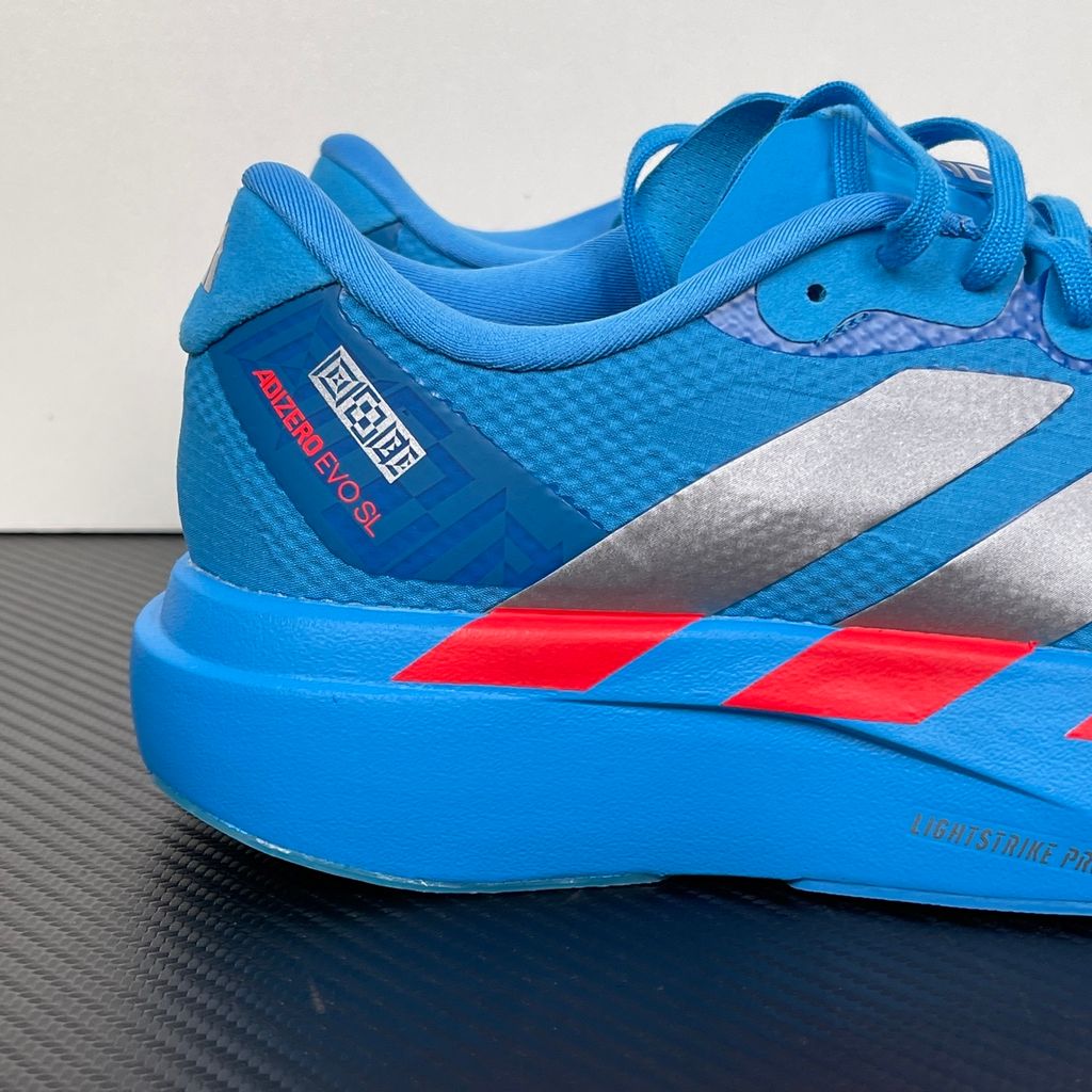 Side profile of the adidas Adizero Evo SL 'Ekiden' in a vibrant Solar Blue colorway, showcasing the breathable mesh upper, prominent Silver Metallic 3-Stripes branding, and the responsive Lightstrike Pro cushioned midsole.