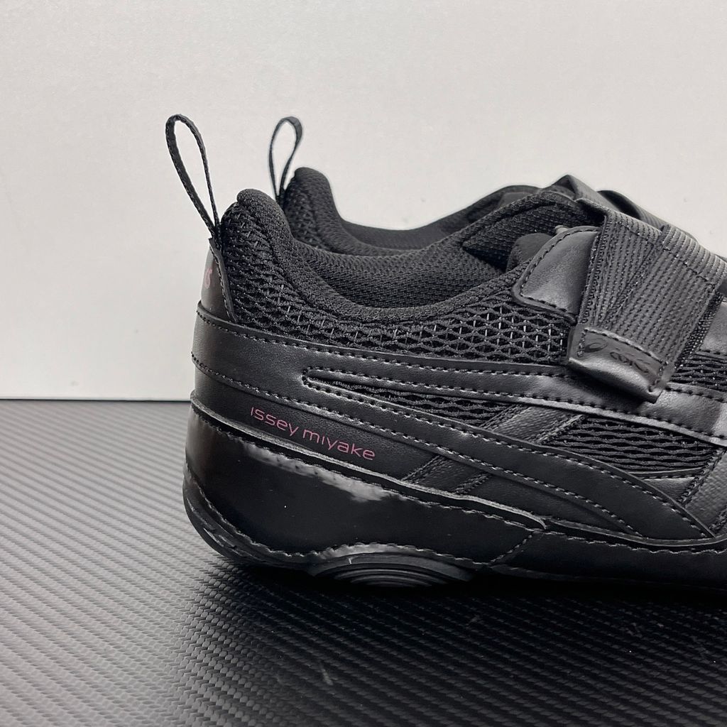 Side profile of the ASICS Hyper Taping x Issey Miyake in all-black, showcasing the sleek minimalist upper, intricate structural tape overlays, and streamlined black midsole.