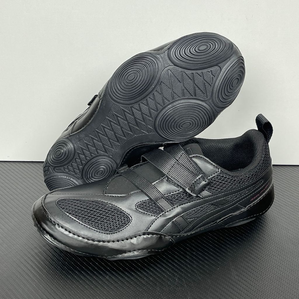 Side profile of the ASICS Hyper Taping x Issey Miyake in all-black, showcasing the sleek minimalist upper, intricate structural tape overlays, and streamlined black midsole.