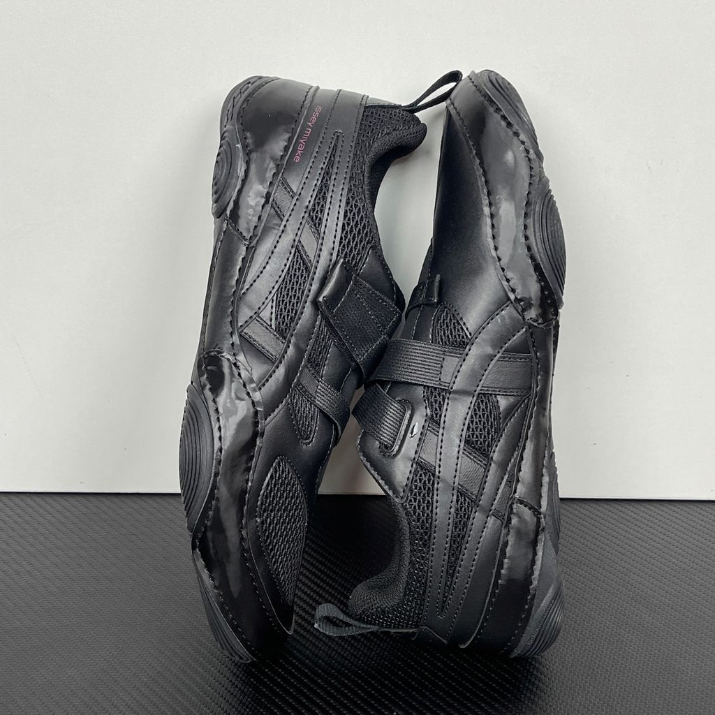 Side profile of the ASICS Hyper Taping x Issey Miyake in all-black, showcasing the sleek minimalist upper, intricate structural tape overlays, and streamlined black midsole.