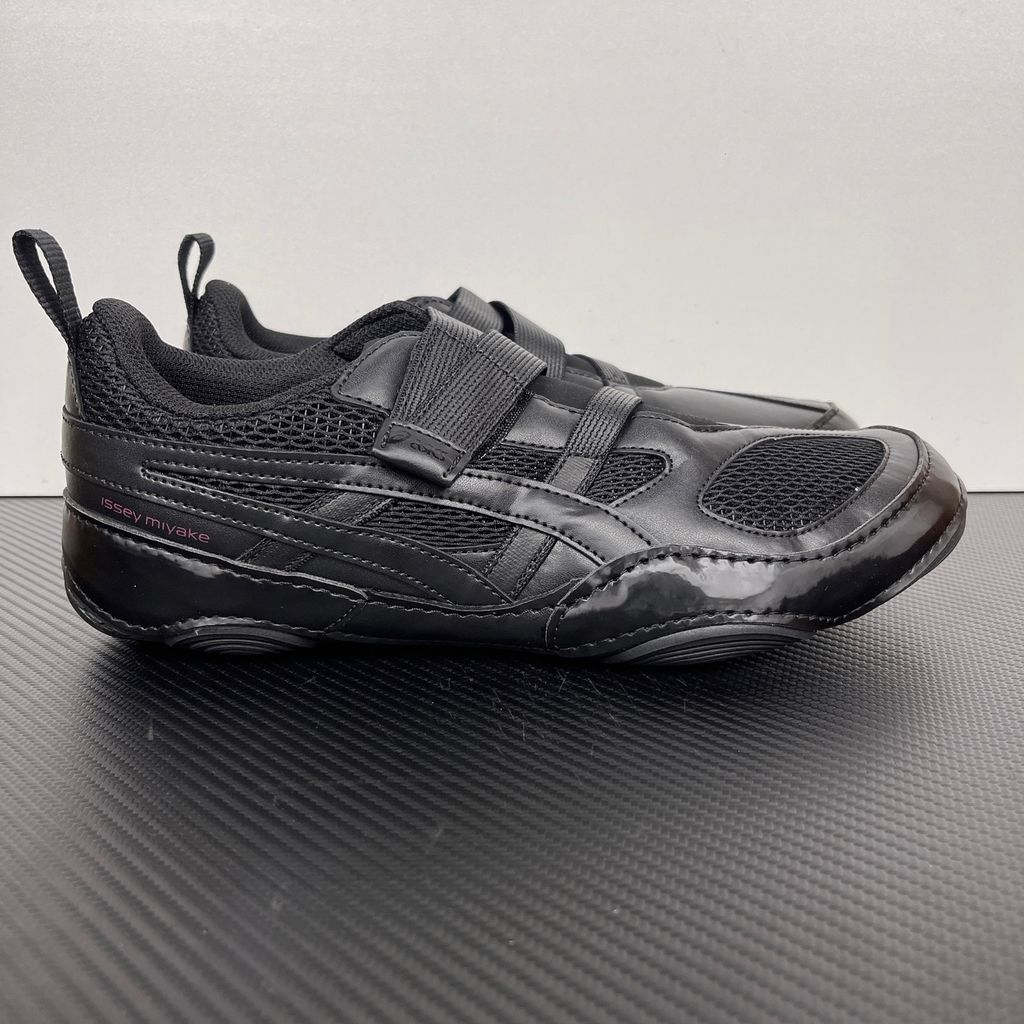 Side profile of the ASICS Hyper Taping x Issey Miyake in all-black, showcasing the sleek minimalist upper, intricate structural tape overlays, and streamlined black midsole.
