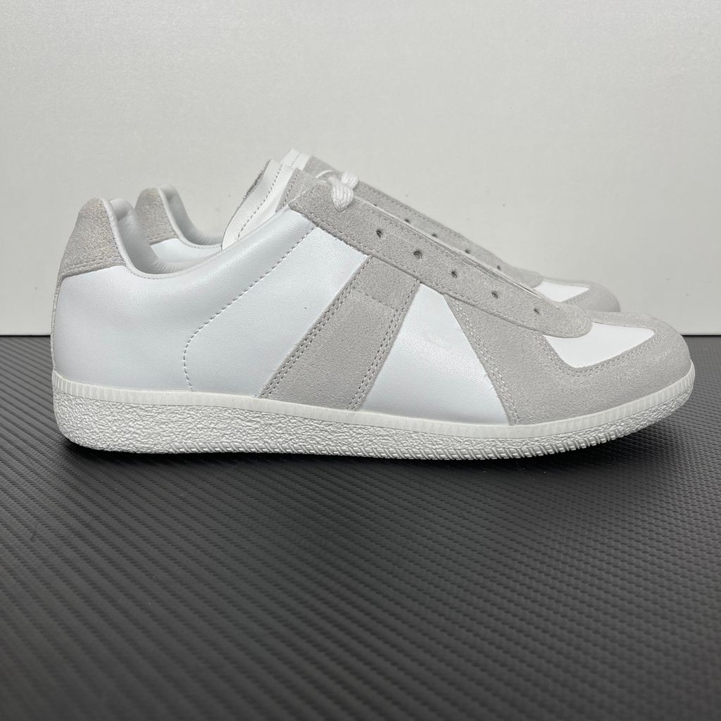 Side profile of the Maison Margiela Replica Low-Top sneakers in white, featuring a premium calfskin leather upper, tonal light grey suede overlays, and a textured white rubber sole.