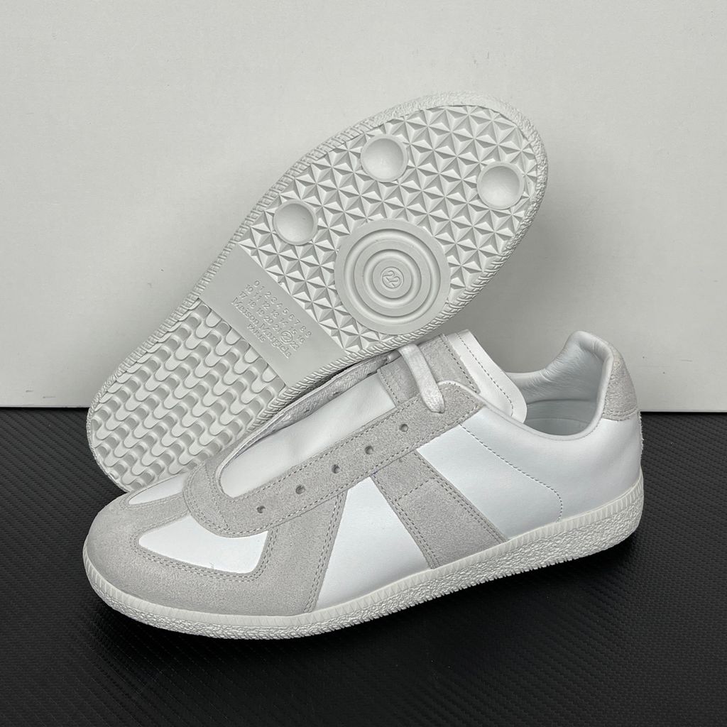 Side profile of the Maison Margiela Replica Low-Top sneakers in white, featuring a premium calfskin leather upper, tonal light grey suede overlays, and a textured white rubber sole.