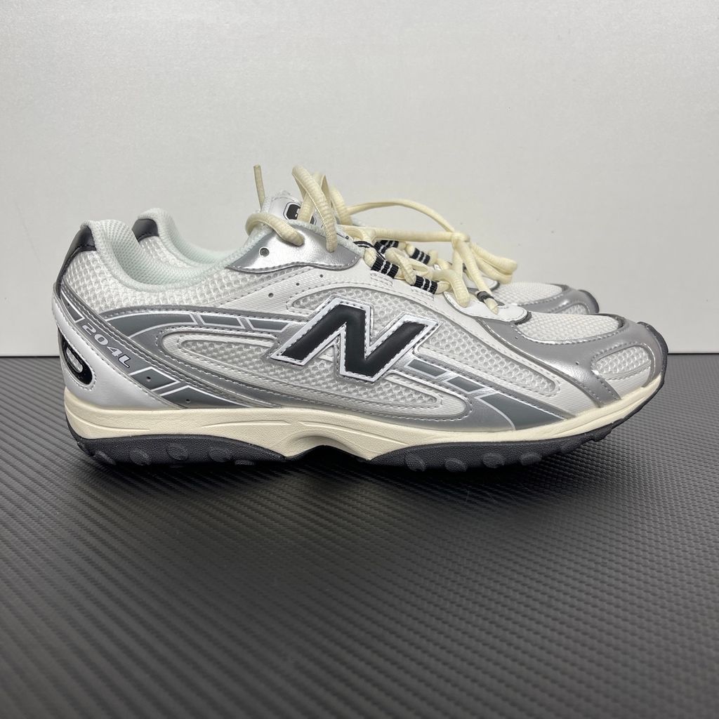 Side profile of the New Balance 204L 'Silver Metallic Black', showcasing the breathable black mesh upper, dynamic silver metallic synthetic overlays, classic 'N' logo, and a sleek, cushioned runner midsole.