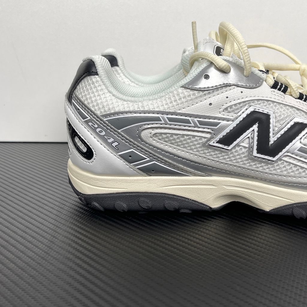 Side profile of the New Balance 204L 'Silver Metallic Black', showcasing the breathable black mesh upper, dynamic silver metallic synthetic overlays, classic 'N' logo, and a sleek, cushioned runner midsole.