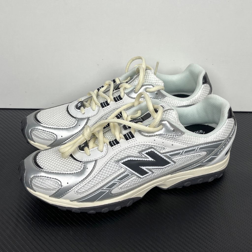 Side profile of the New Balance 204L 'Silver Metallic Black', showcasing the breathable black mesh upper, dynamic silver metallic synthetic overlays, classic 'N' logo, and a sleek, cushioned runner midsole.