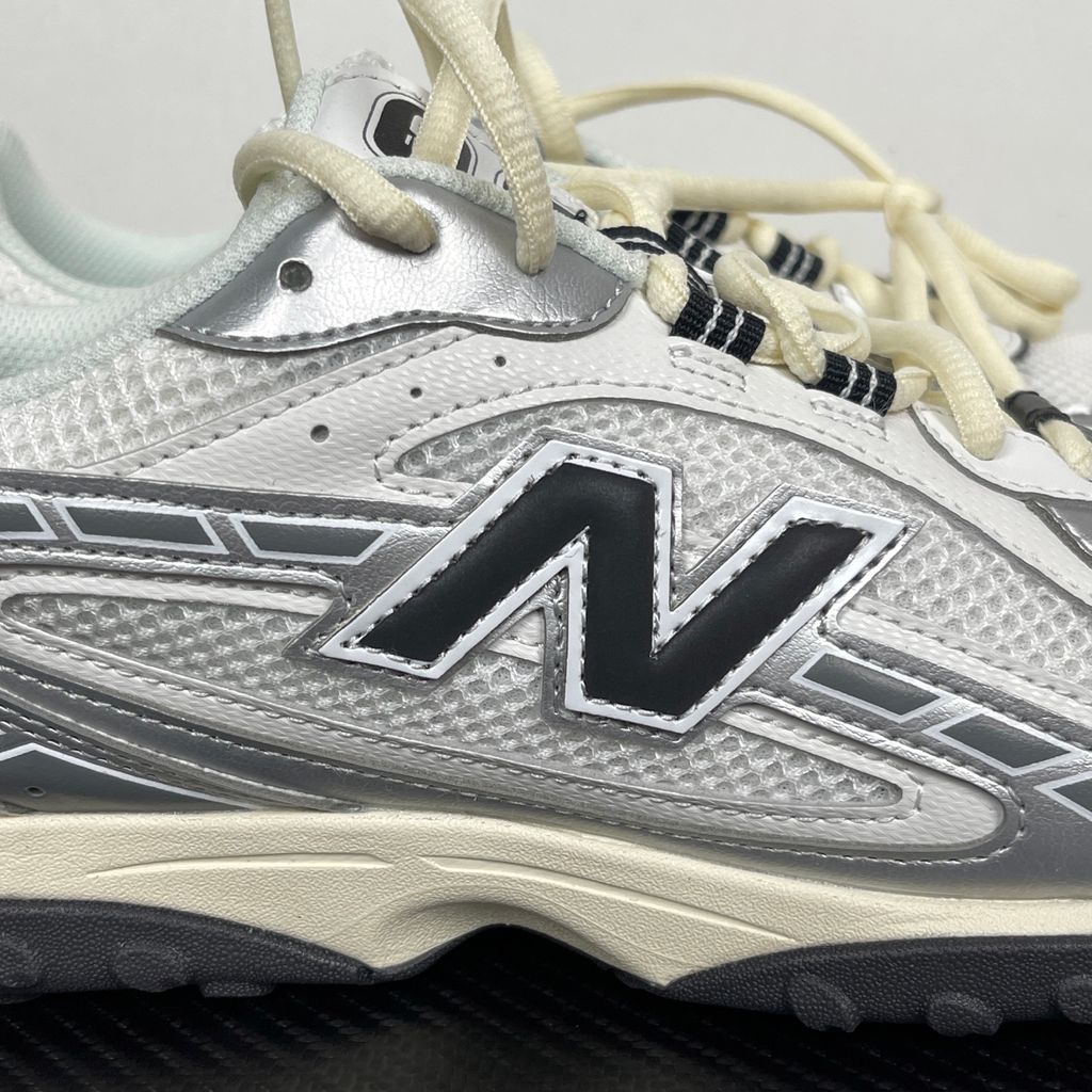 Side profile of the New Balance 204L 'Silver Metallic Black', showcasing the breathable black mesh upper, dynamic silver metallic synthetic overlays, classic 'N' logo, and a sleek, cushioned runner midsole.