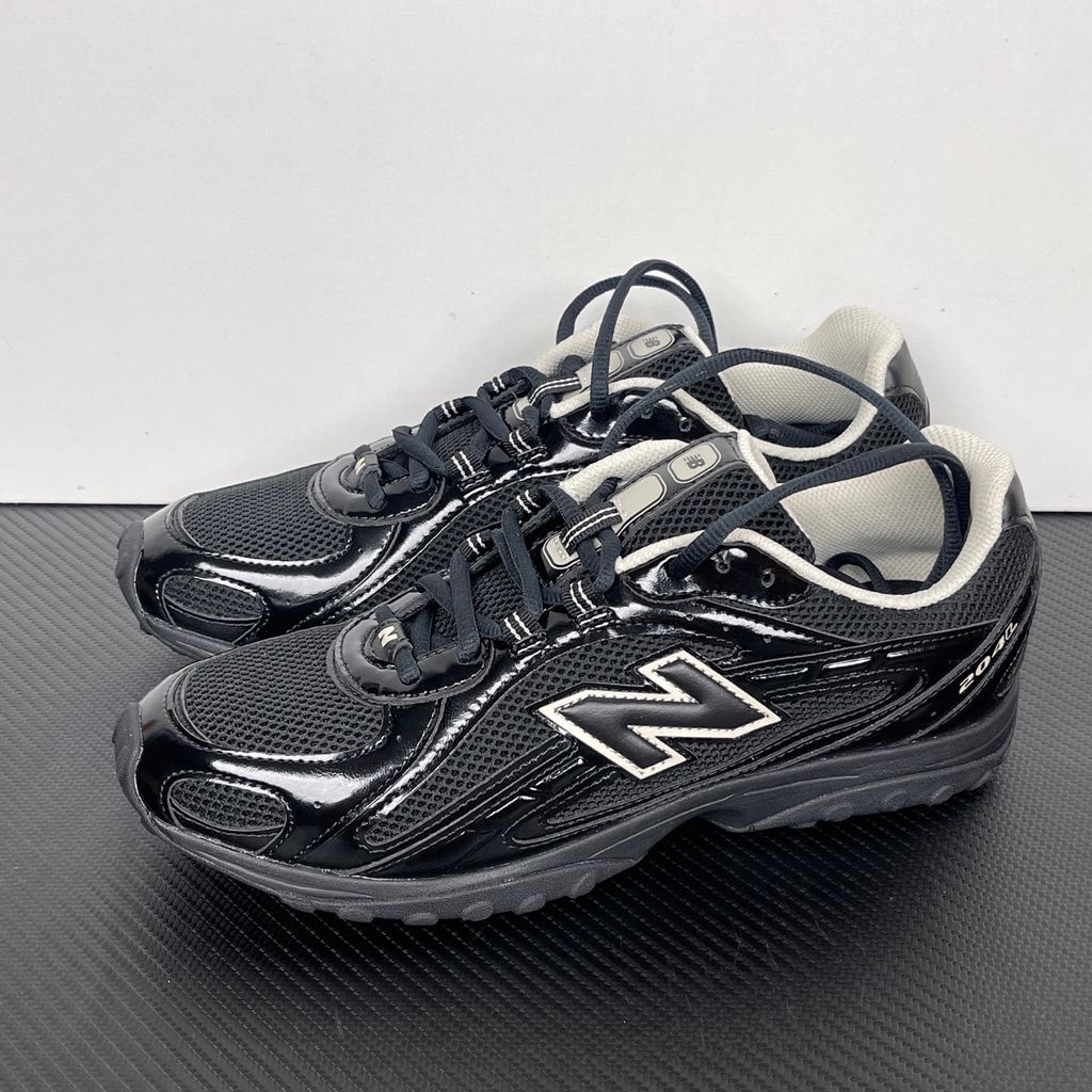 Side profile of the New Balance 204L 'Black Timberwolf', showcasing the breathable black mesh upper, dynamic taupe-grey Timberwolf synthetic overlays, classic 'N' logo, and a sleek, cushioned runner midsole.