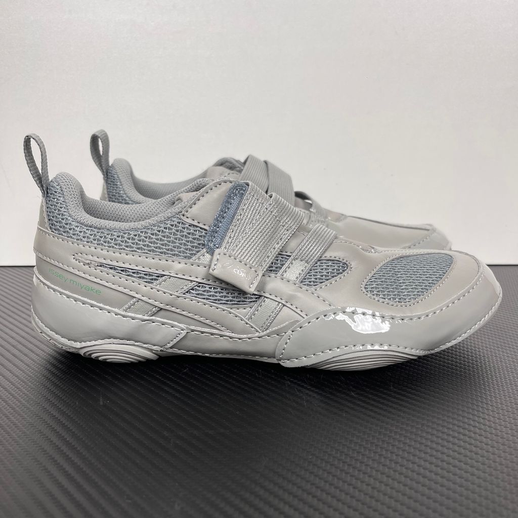 Side profile of the ASICS Hyper Taping x Issey Miyake in a monochromatic grey colorway, showcasing the sleek minimalist upper, intricate structural tape overlays, and streamlined tonal midsole.