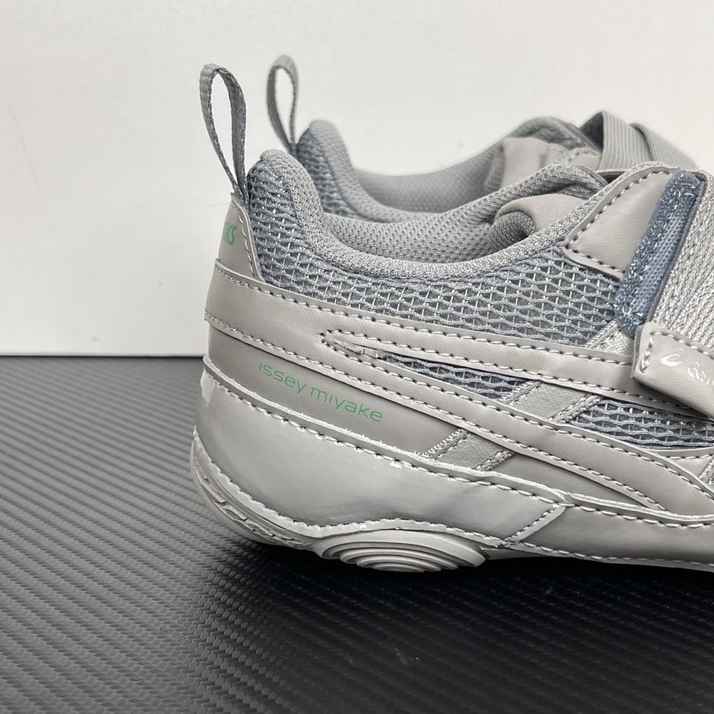 Side profile of the ASICS Hyper Taping x Issey Miyake in a monochromatic grey colorway, showcasing the sleek minimalist upper, intricate structural tape overlays, and streamlined tonal midsole.