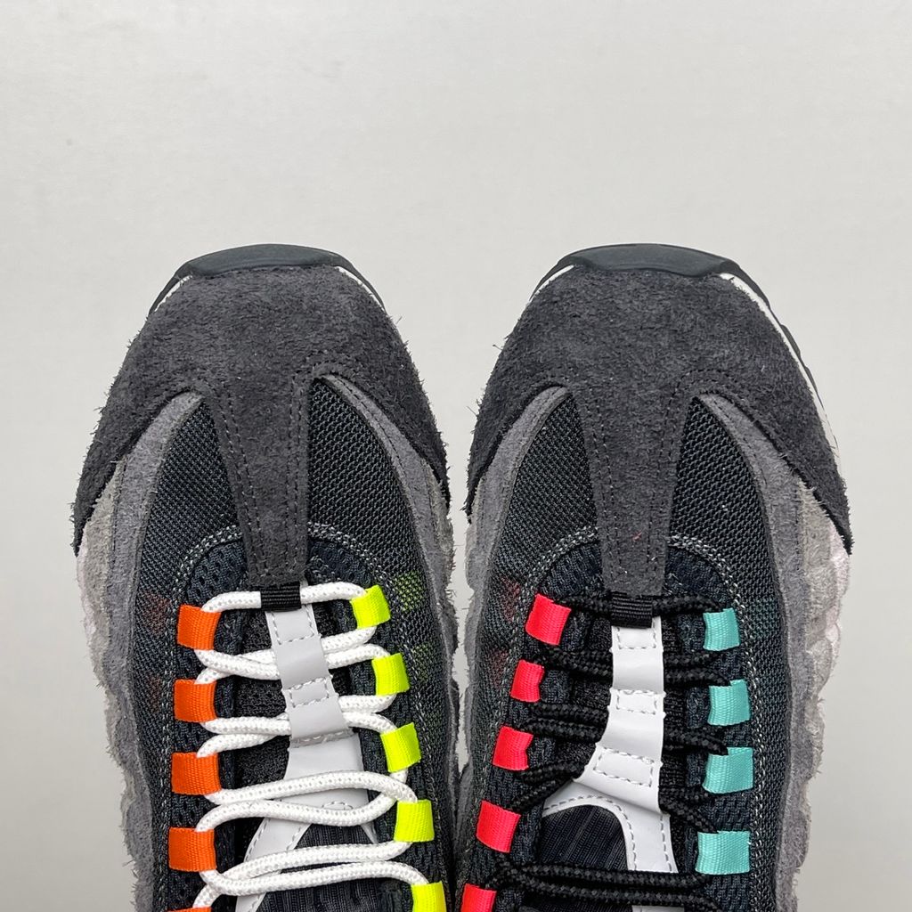 Side profiles of the left and right Nike Air Max 95 OG 'Big Bubble' Greedy (2026) sneakers, showcasing the asymmetrical, mismatched multi-color gradient uppers and the exaggerated visible Air units in the black midsole.
