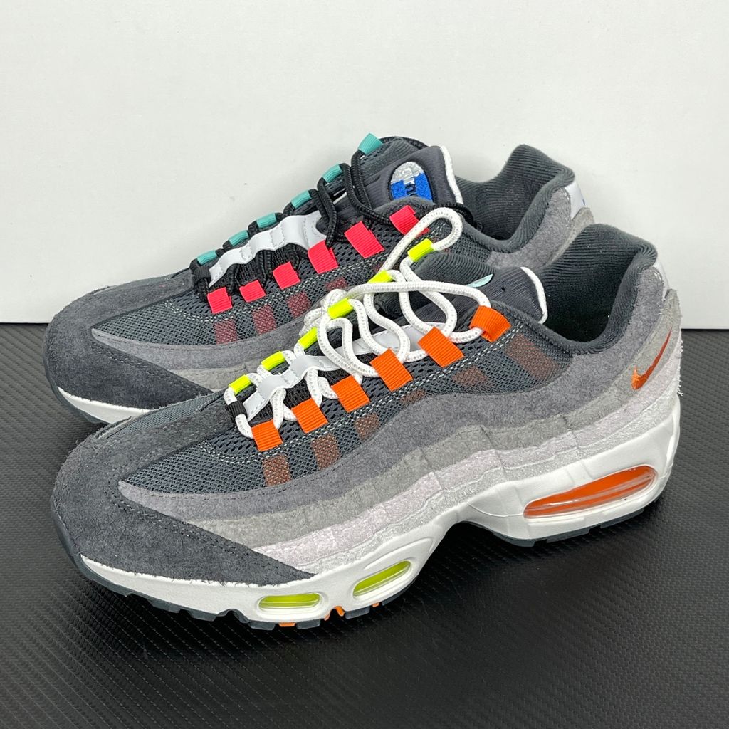 Side profiles of the left and right Nike Air Max 95 OG 'Big Bubble' Greedy (2026) sneakers, showcasing the asymmetrical, mismatched multi-color gradient uppers and the exaggerated visible Air units in the black midsole.