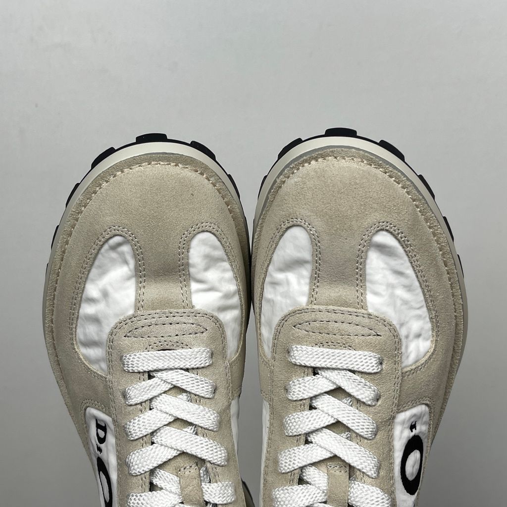 Side profile of the Dior Squash Sneaker, showcasing the white nylon base, beige suede overlays, prominent black "DiOr" side logo, and chunky white midsole with a black lugged outsole.