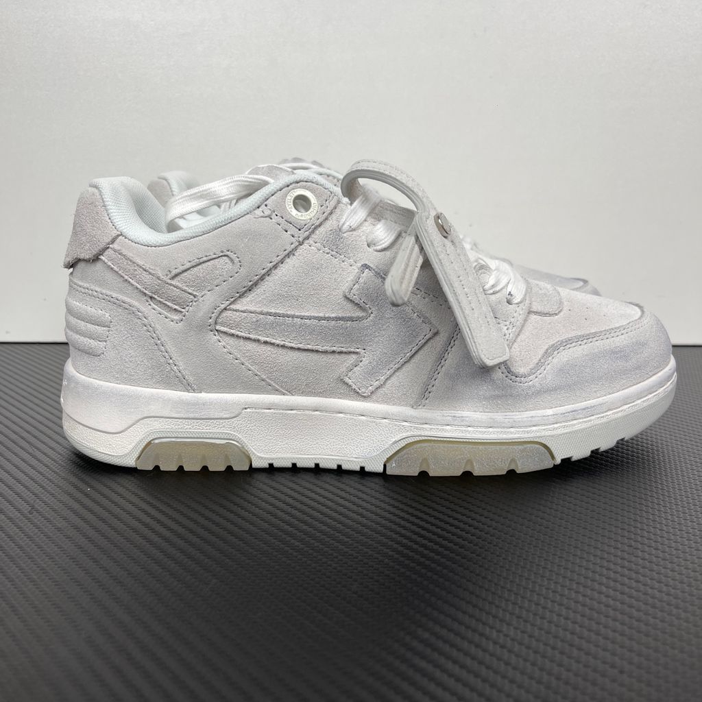 Side profile of the Off-White Out Of Office sneaker in Light Grey, showcasing the tonal distressed suede upper, signature Arrow logo, leather tag detail on the laces, and a white midsole featuring translucent gel inserts.