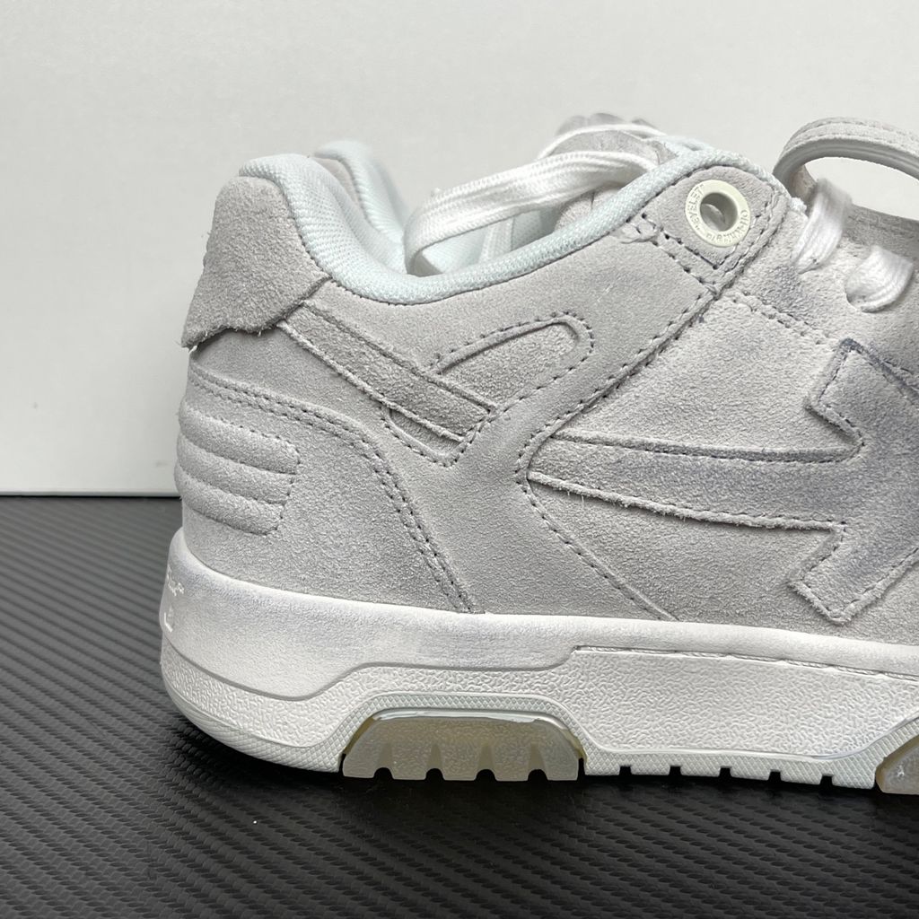 Side profile of the Off-White Out Of Office sneaker in Light Grey, showcasing the tonal distressed suede upper, signature Arrow logo, leather tag detail on the laces, and a white midsole featuring translucent gel inserts.