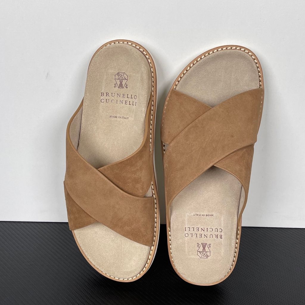 Top-down view of the Brunello Cucinelli suede sandals, showcasing the criss-cross bronze brown straps, soft beige footbed with official stamped branding, and meticulous Italian welt stitching.