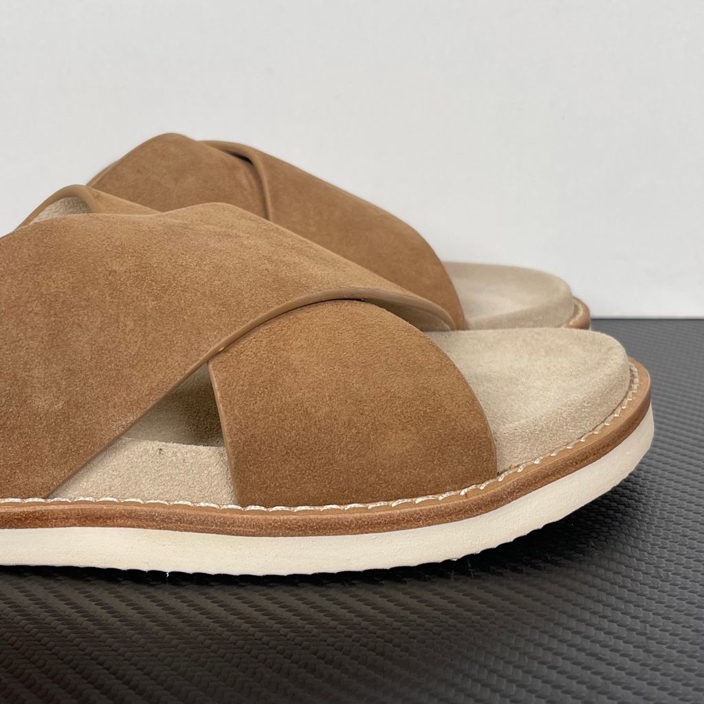 Top-down view of the Brunello Cucinelli suede sandals, showcasing the criss-cross bronze brown straps, soft beige footbed with official stamped branding, and meticulous Italian welt stitching.
