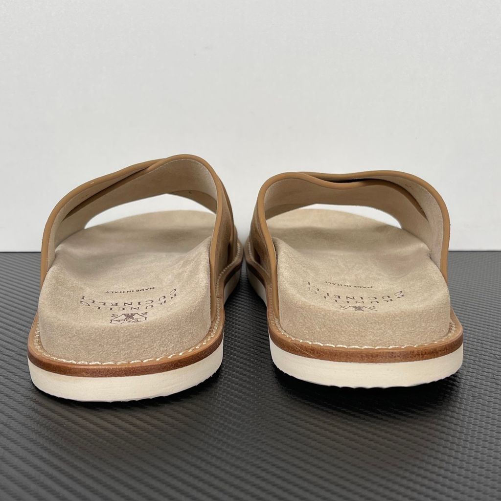 Top-down view of the Brunello Cucinelli suede sandals, showcasing the criss-cross bronze brown straps, soft beige footbed with official stamped branding, and meticulous Italian welt stitching.
