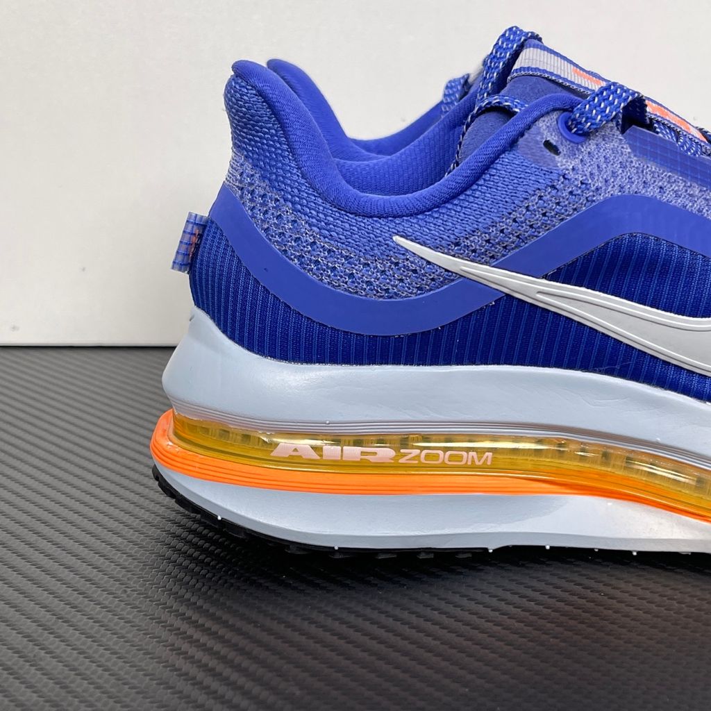Side profile of the Nike Air Zoom Pegasus Premium, showcasing the vibrant Lapis blue engineered mesh upper, crisp white Nike Swoosh, energetic Total Orange accents, and the groundbreaking sculpted visible Zoom Air unit running through the midsole.