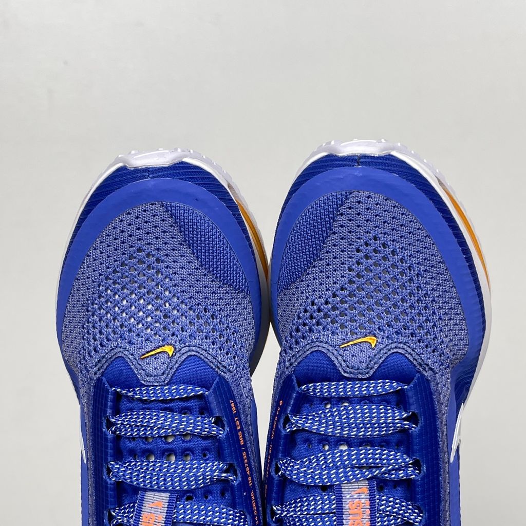 Side profile of the Nike Air Zoom Pegasus Premium, showcasing the vibrant Lapis blue engineered mesh upper, crisp white Nike Swoosh, energetic Total Orange accents, and the groundbreaking sculpted visible Zoom Air unit running through the midsole.