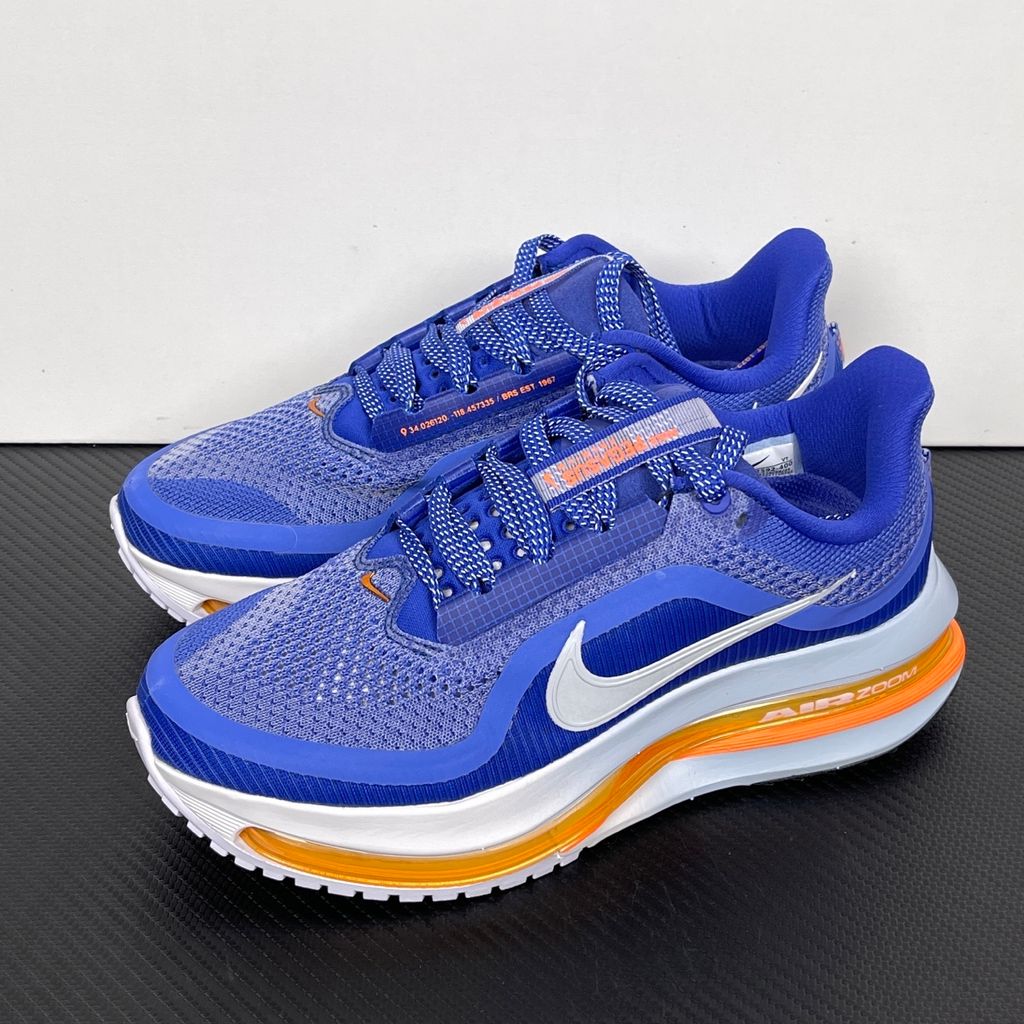 Side profile of the Nike Air Zoom Pegasus Premium, showcasing the vibrant Lapis blue engineered mesh upper, crisp white Nike Swoosh, energetic Total Orange accents, and the groundbreaking sculpted visible Zoom Air unit running through the midsole.
