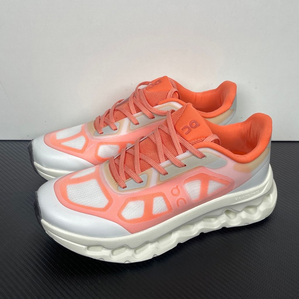 Side profile of the On Running Cloudtilt Remix sneaker, showcasing the vibrant warm orange 'Sunstone' mixed-material upper, quick-adjust speed lacing, and the crisp Ivory white CloudTec Phase® collapsing midsole.