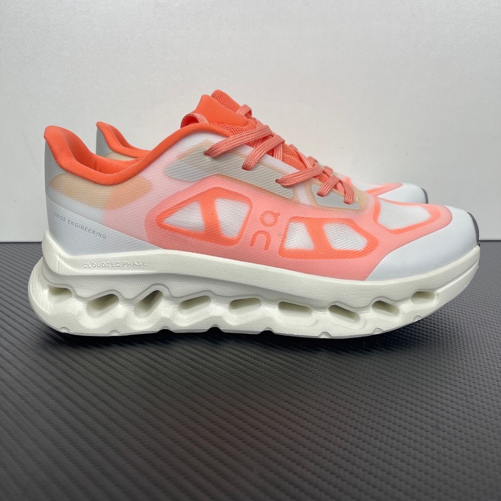 Side profile of the On Running Cloudtilt Remix sneaker, showcasing the vibrant warm orange 'Sunstone' mixed-material upper, quick-adjust speed lacing, and the crisp Ivory white CloudTec Phase® collapsing midsole.