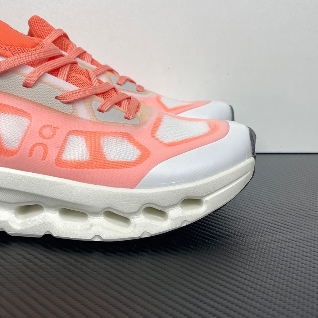 Side profile of the On Running Cloudtilt Remix sneaker, showcasing the vibrant warm orange 'Sunstone' mixed-material upper, quick-adjust speed lacing, and the crisp Ivory white CloudTec Phase® collapsing midsole.
