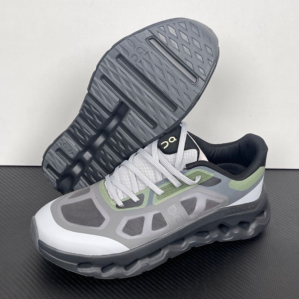 Side profile of the On Running Cloudtilt Remix sneaker, showcasing the mixed-material upper in dark grey and white with subtle green mesh undertones, quick-adjust speed lacing, and the distinctive dark grey CloudTec Phase® collapsing midsole.