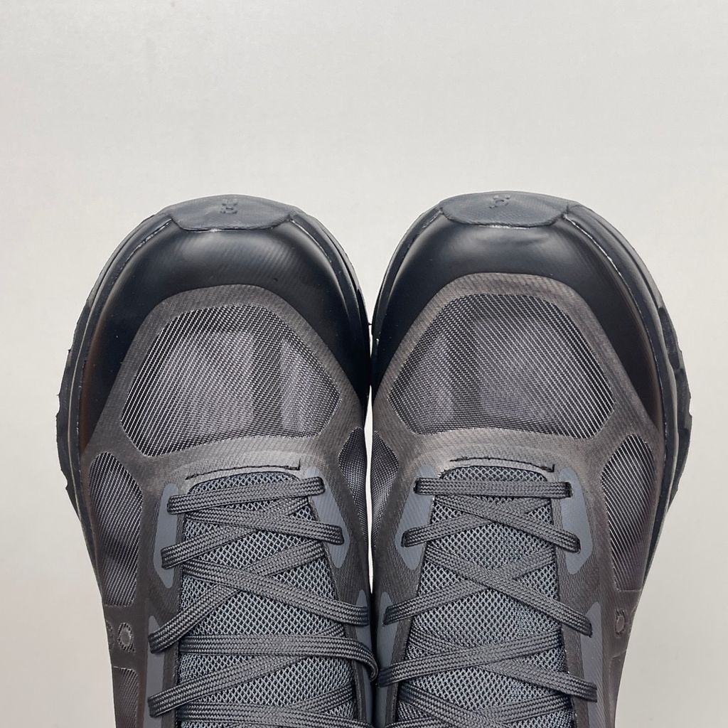 Side profile of the On Running Cloudtilt Remix sneaker in a monochromatic 'Triple Black' colorway, showcasing the mixed-material mesh and synthetic upper, quick-adjust speed lacing, and the stealthy black CloudTec Phase® collapsing midsole.