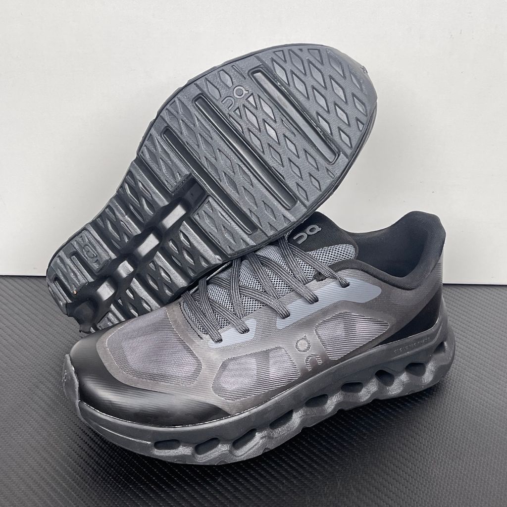 Side profile of the On Running Cloudtilt Remix sneaker in a monochromatic 'Triple Black' colorway, showcasing the mixed-material mesh and synthetic upper, quick-adjust speed lacing, and the stealthy black CloudTec Phase® collapsing midsole.