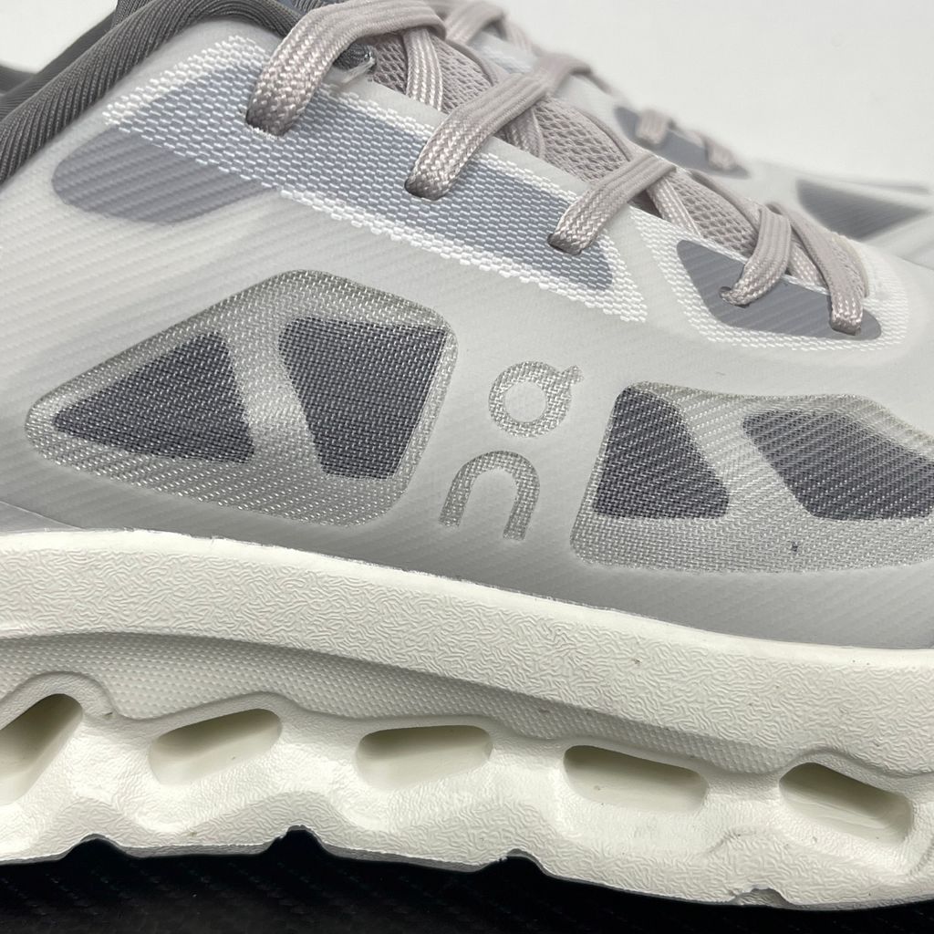 ide profile of the On Running Cloudtilt Remix sneaker, showcasing the mixed-material upper featuring a tonal grey breathable mesh base with matching grey synthetic overlays, speed lacing, and the distinctive white CloudTec Phase® collapsing midsole.