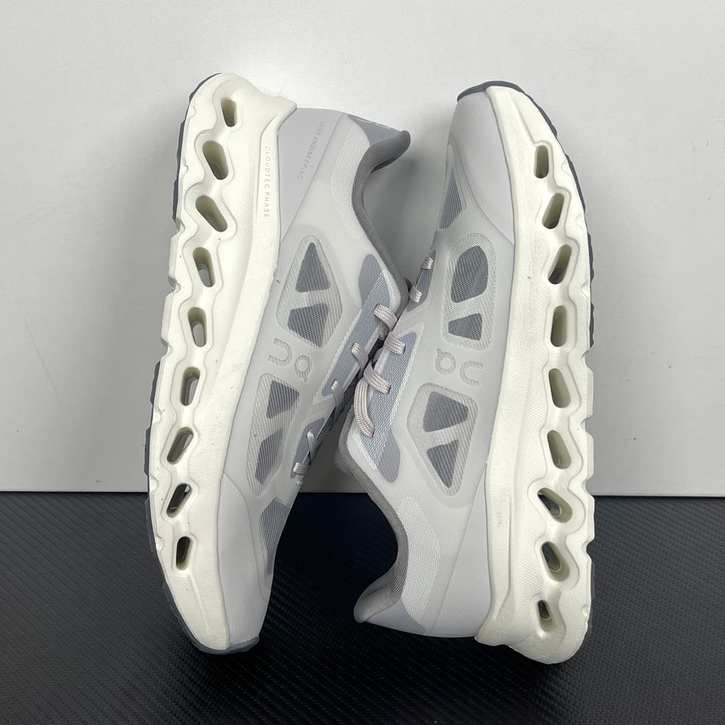 ide profile of the On Running Cloudtilt Remix sneaker, showcasing the mixed-material upper featuring a tonal grey breathable mesh base with matching grey synthetic overlays, speed lacing, and the distinctive white CloudTec Phase® collapsing midsole.