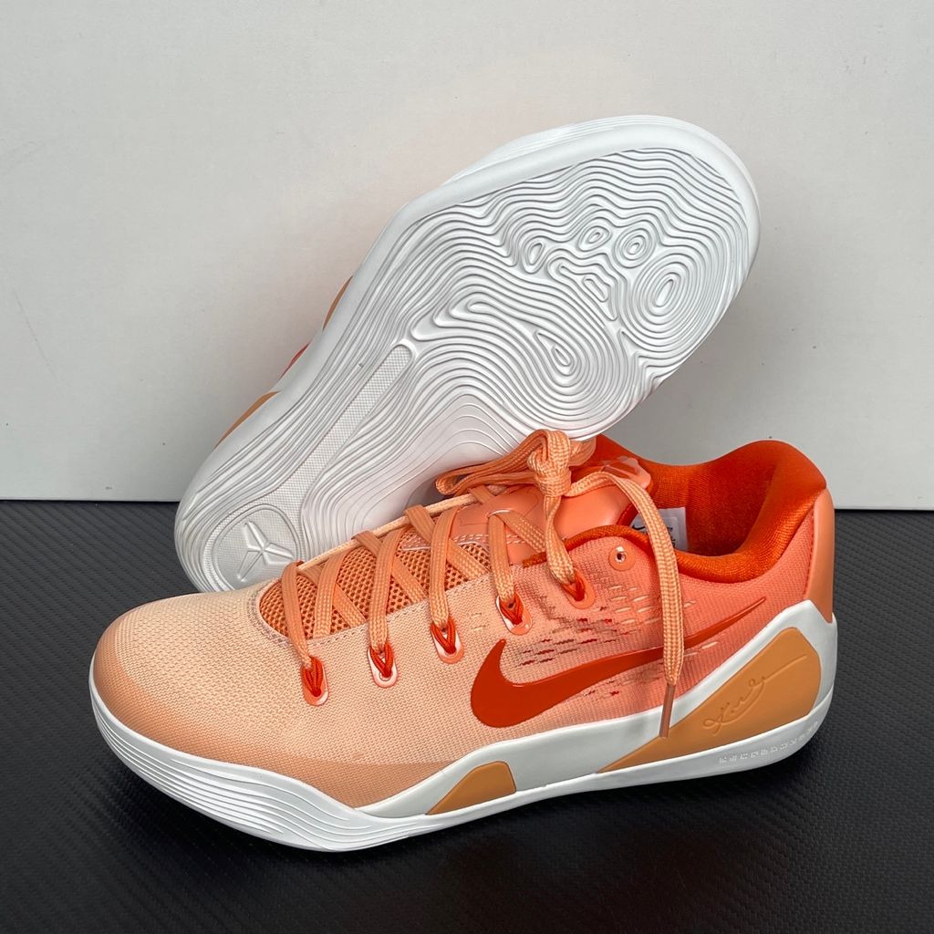 Side profile of the Nike Kobe 9 EM Low Protro, showcasing the vibrant orange Engineered Mesh upper, black Nike Swoosh, carbon fiber heel counter, and the signature pressure-mapped traction pattern on the outsole.