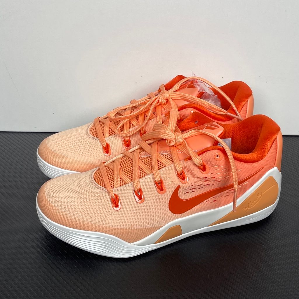 Side profile of the Nike Kobe 9 EM Low Protro, showcasing the vibrant orange Engineered Mesh upper, black Nike Swoosh, carbon fiber heel counter, and the signature pressure-mapped traction pattern on the outsole.