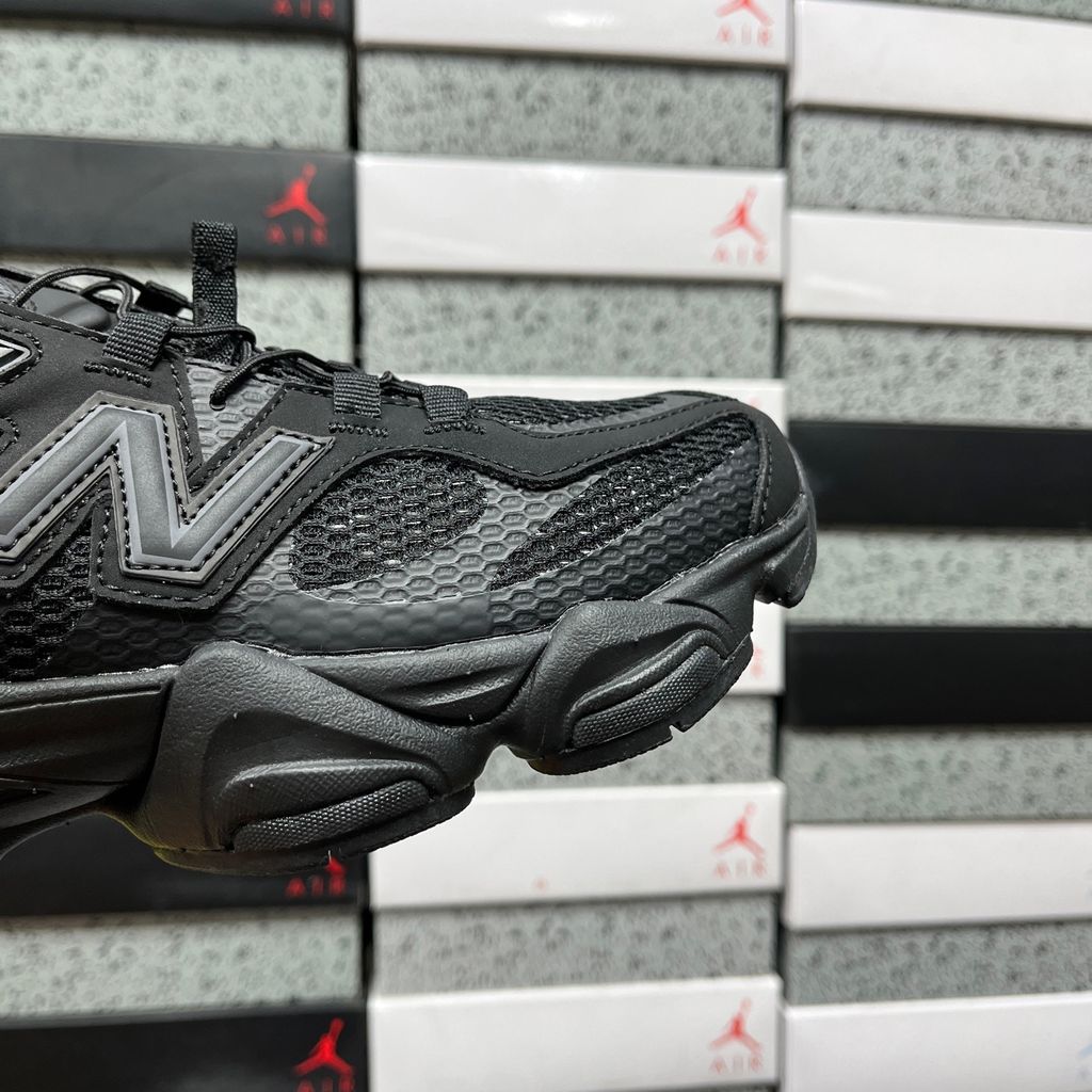 Side profile of the New Balance 9060 sneaker in the 'Summer Black' colorway, showcasing the retro-futuristic chunky midsole, black breathable mesh upper with tonal suede overlays, and the signature metallic 'N' logo on the side panel.