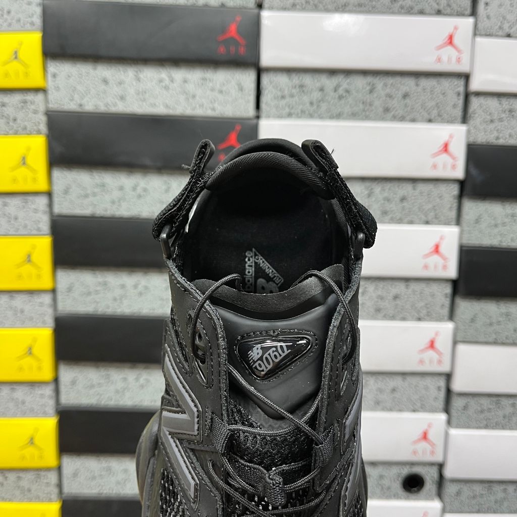Side profile of the New Balance 9060 sneaker in the 'Summer Black' colorway, showcasing the retro-futuristic chunky midsole, black breathable mesh upper with tonal suede overlays, and the signature metallic 'N' logo on the side panel.