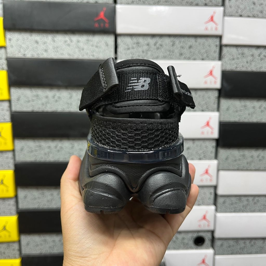 Side profile of the New Balance 9060 sneaker in the 'Summer Black' colorway, showcasing the retro-futuristic chunky midsole, black breathable mesh upper with tonal suede overlays, and the signature metallic 'N' logo on the side panel.