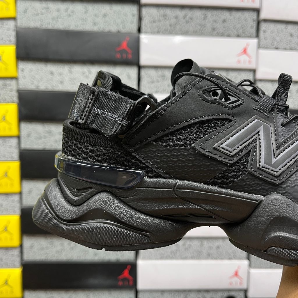 Side profile of the New Balance 9060 sneaker in the 'Summer Black' colorway, showcasing the retro-futuristic chunky midsole, black breathable mesh upper with tonal suede overlays, and the signature metallic 'N' logo on the side panel.