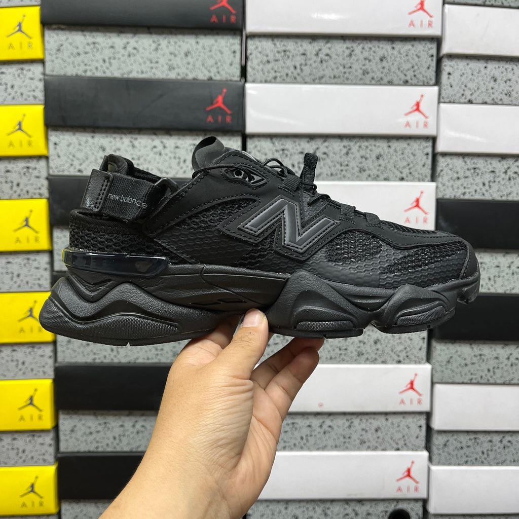 Side profile of the New Balance 9060 sneaker in the 'Summer Black' colorway, showcasing the retro-futuristic chunky midsole, black breathable mesh upper with tonal suede overlays, and the signature metallic 'N' logo on the side panel.