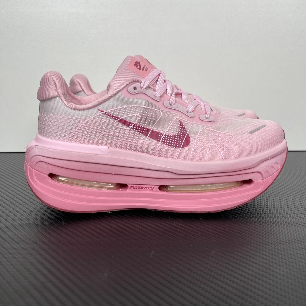 Side profile of the Nike Vomero Premium sneaker in the 'Pink Foam Light Magenta' colorway, showcasing the heavily layered breathable mesh upper, vibrant pink synthetic overlays, the iconic plastic midfoot cage, and the sculpted Cushlon midsole.
