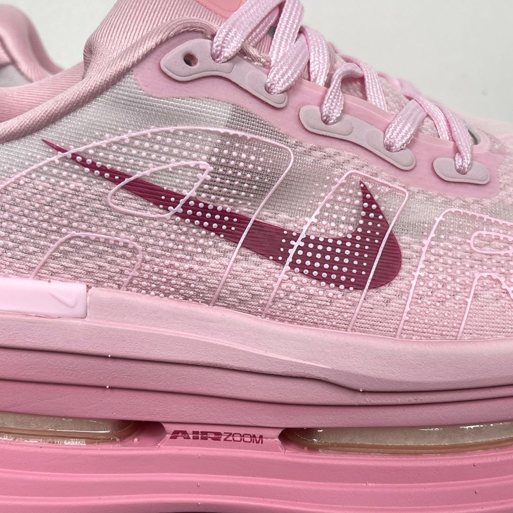 Side profile of the Nike Vomero Premium sneaker in the 'Pink Foam Light Magenta' colorway, showcasing the heavily layered breathable mesh upper, vibrant pink synthetic overlays, the iconic plastic midfoot cage, and the sculpted Cushlon midsole.