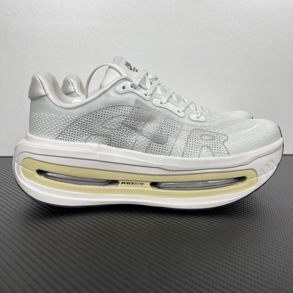 Side profile of the Nike Vomero Premium sneaker in the clean 'Chalk' colorway, showcasing the heavily layered breathable mesh upper, tonal off-white synthetic overlays, the iconic plastic midfoot cage, and the sculpted Cushlon midsole.