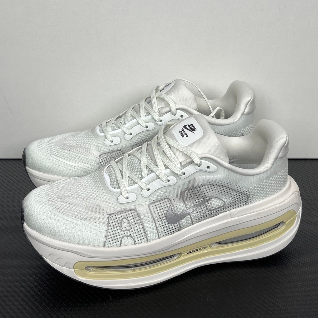 Side profile of the Nike Vomero Premium sneaker in the clean 'Chalk' colorway, showcasing the heavily layered breathable mesh upper, tonal off-white synthetic overlays, the iconic plastic midfoot cage, and the sculpted Cushlon midsole.