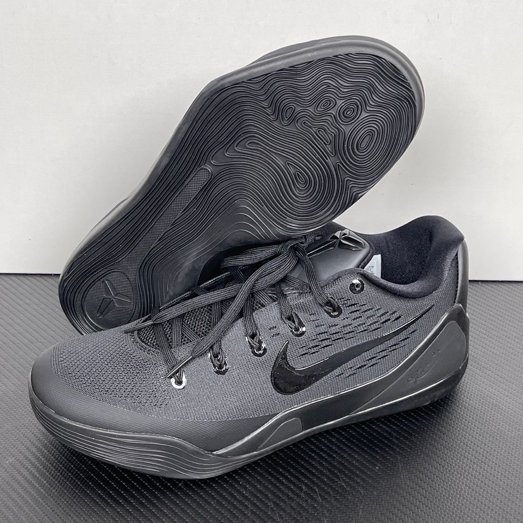 Side profile of the Nike Kobe 9 EM Low Protro TB sneaker in a monochromatic 'Triple Black' colorway, showcasing the stealthy Engineered Mesh upper, tonal black Swoosh, carbon fiber heel counter, and the signature black pressure-mapped outsole.